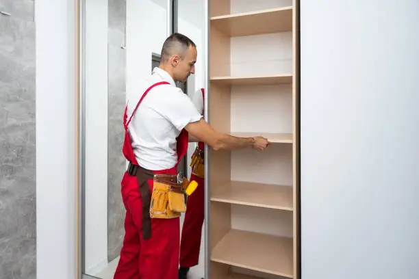 Professional custom closet systems being installed in a small walk in closet by a closet company