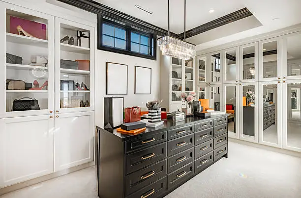 A luxurious custom walk-in closet with an island dresser, floor-to-ceiling cabinets, and LED lighting