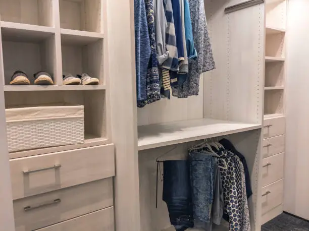 U-shaped closet systems for walk-in closets featuring mixed shelving and warm lighting