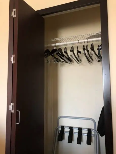 A close-up of a guest closet with luggage racks, hanging rods, and lockable drawers, designed for short-term stays.