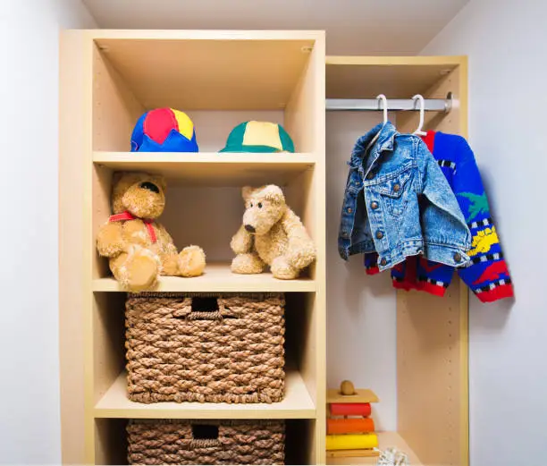A walk-in closet for kids with play space, safe storage, and colorful finishes, designed for sibling or shared use.