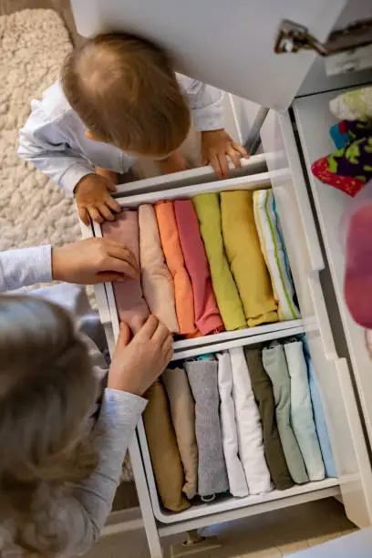 A close-up of a shared closet with color-coded drawers, dual rods, and labeled bins for two siblings’ belongings.