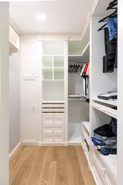 A small walk-in closet with compact, stylish cabinets and shelves, designed for efficient storage