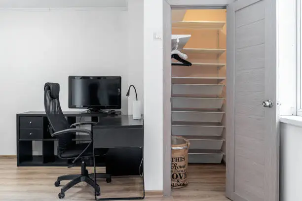 A small walk-in closet converted into a functional office with a foldable desk and organized storage
