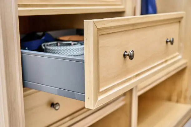 A close-up of a custom wardrobe with premium wood finishes, adjustable rods, and pull-out accessories