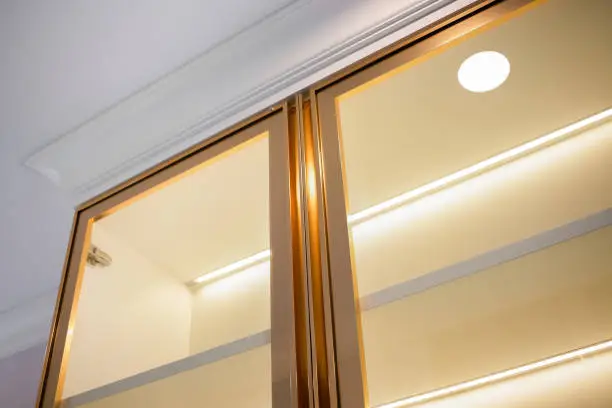 A close-up of a media center with glass doors, integrated lighting, and adjustable shelves for devices and decor