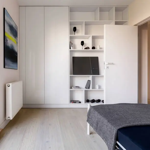 A compact media center in a small bedroom with wall-mounted shelves and hidden storage, perfect for tight spaces