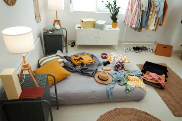 A cluttered small bedroom with scattered clothes, highlighting the need for an organized reach-in closet