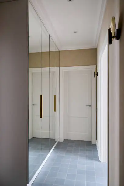 A compact walk-in closet with mirrored doors and high-end finishes, designed for a small space
